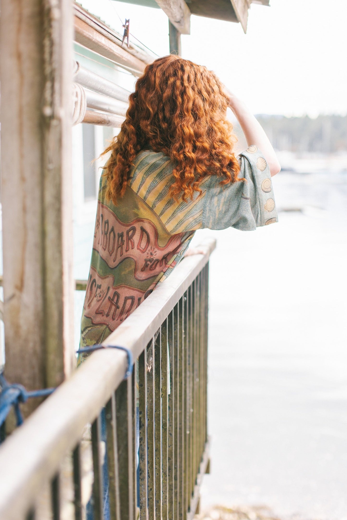 Lightweight duster featuring antique sunrise sky, mermaid, shell, and soaring birds artwork, shown on model at the beach – Market of Stars