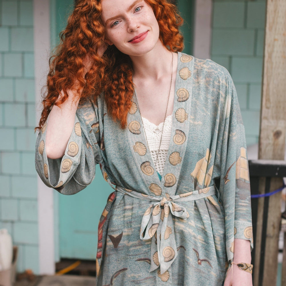 
                  
                    Lightweight duster featuring antique sunrise sky, mermaid, shell, and soaring birds artwork, shown on model at the beach – Market of Stars
                  
                