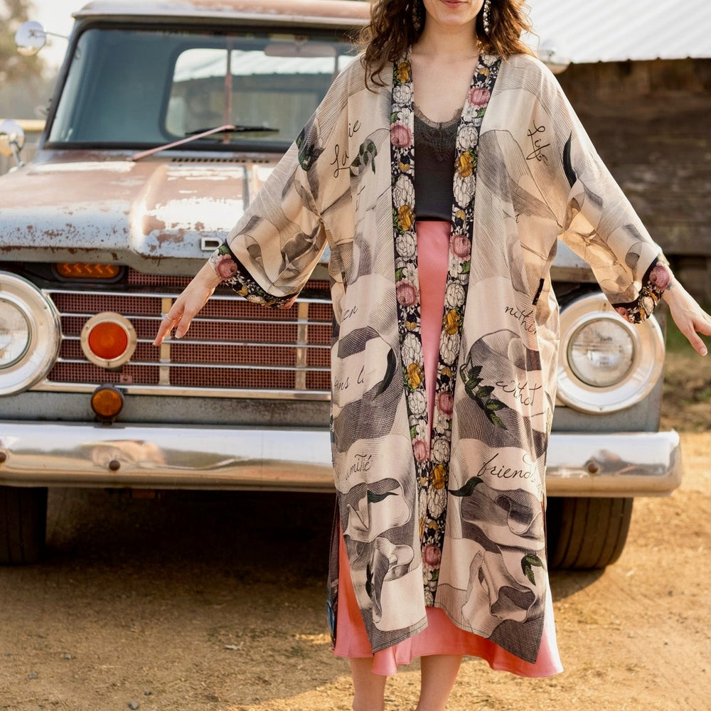 
                  
                    Clasped hands, radiant sun rays, and blooming florals in a joyful Victorian collage on our full-length Take My Hand Opera Duster
                  
                