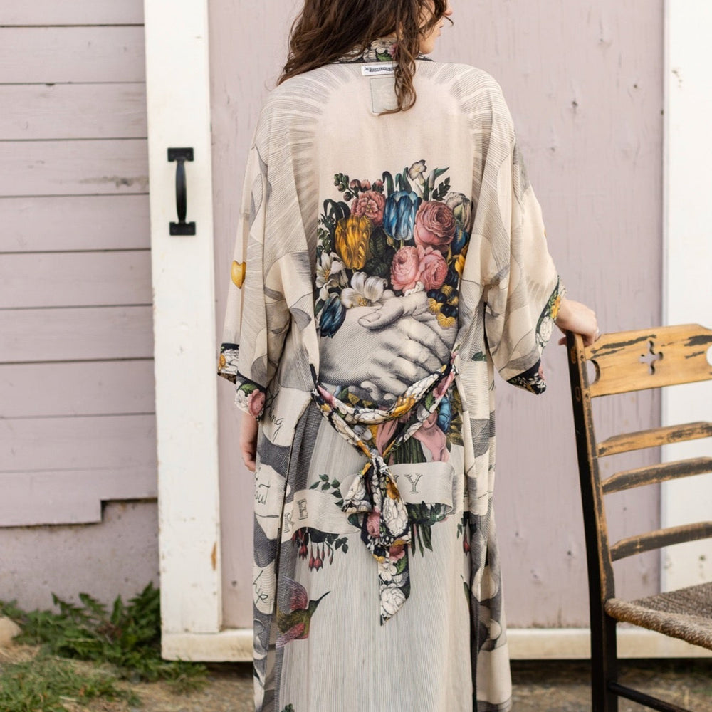 
                  
                    Clasped hands, radiant sun rays, and blooming florals in a joyful Victorian collage on our full-length Take My Hand Opera Duster
                  
                