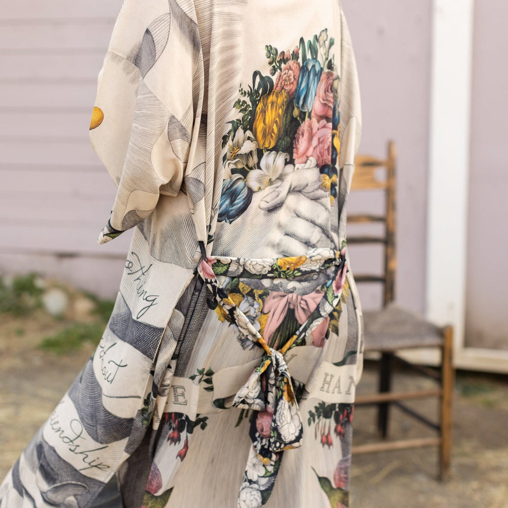 
                  
                    Clasped hands, radiant sun rays, and blooming florals in a joyful Victorian collage on our full-length Take My Hand Opera Duster
                  
                