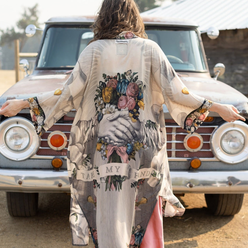 
                  
                    Clasped hands, radiant sun rays, and blooming florals in a joyful Victorian collage on our full-length Take My Hand Opera Duster
                  
                