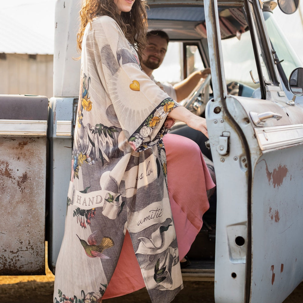 
                  
                    Clasped hands, radiant sun rays, and blooming florals in a joyful Victorian collage on our full-length Take My Hand Opera Duster
                  
                