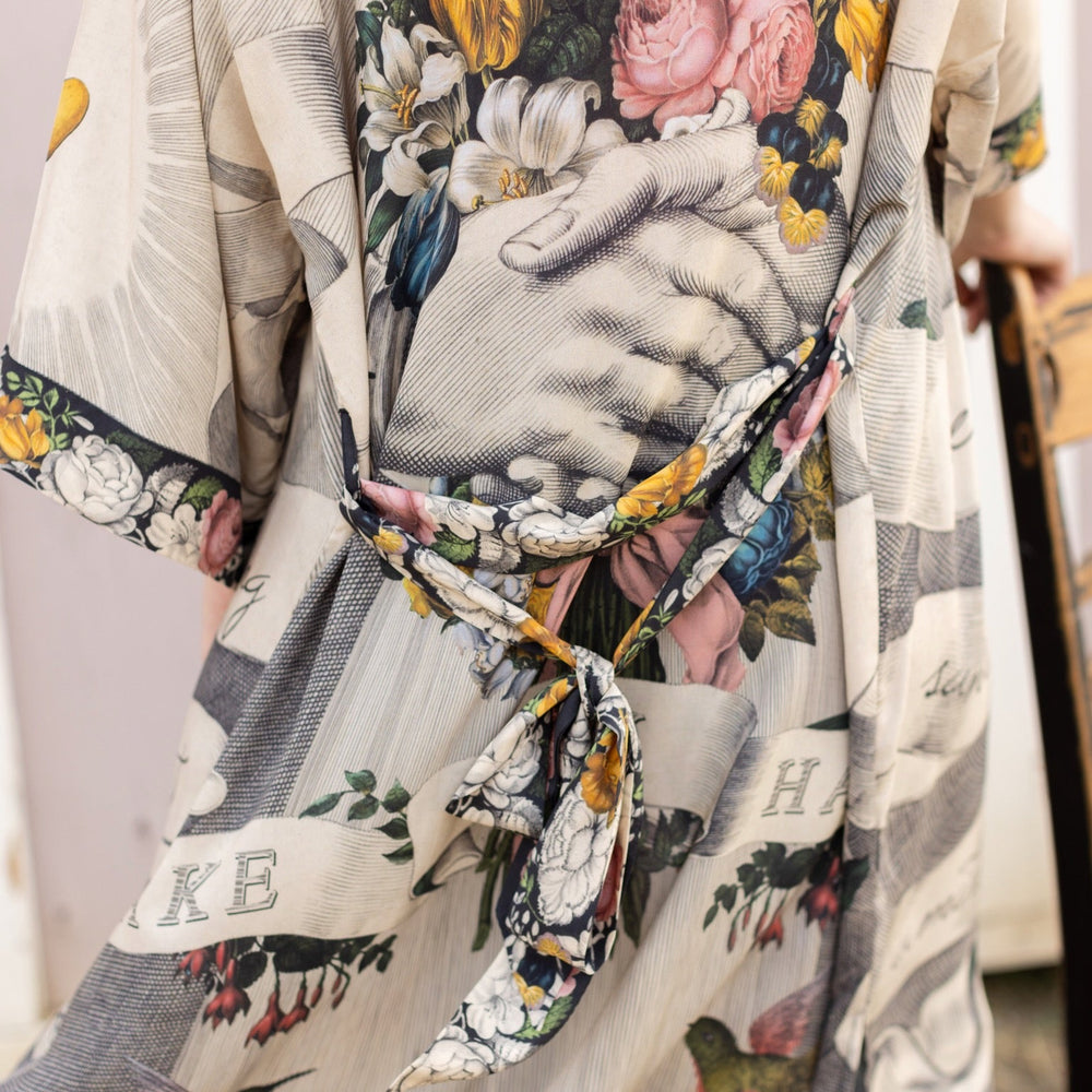 
                  
                    Clasped hands, radiant sun rays, and blooming florals in a joyful Victorian collage on our full-length Take My Hand Opera Duster
                  
                