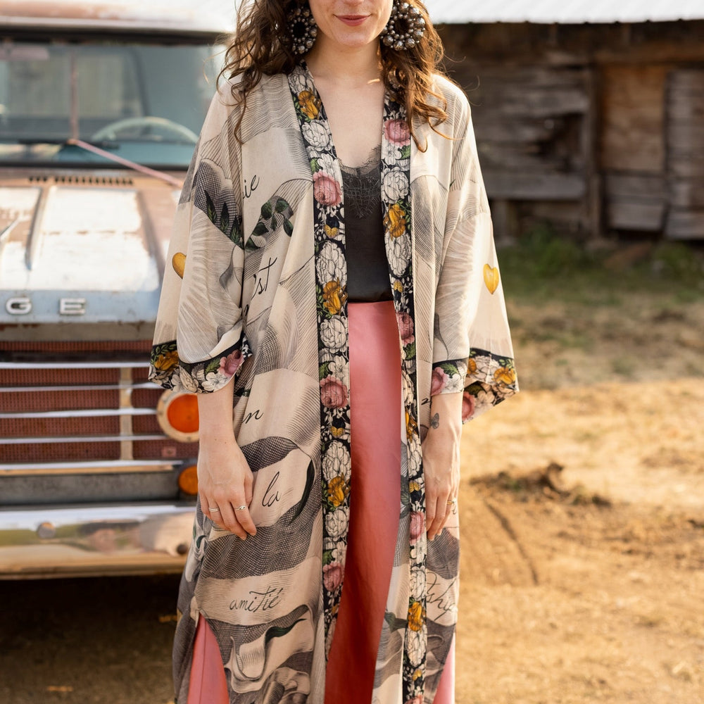
                  
                    Clasped hands, radiant sun rays, and blooming florals in a joyful Victorian collage on our full-length Take My Hand Opera Duster
                  
                