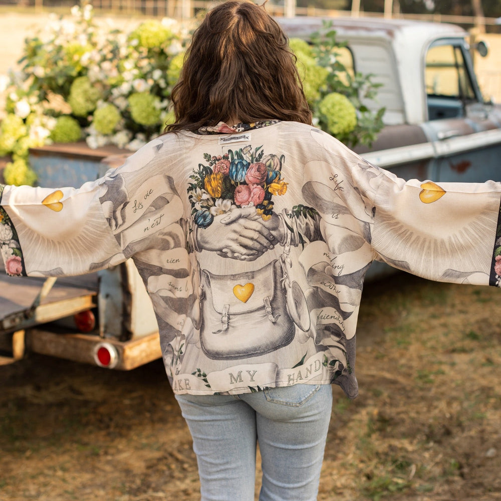 
                  
                    A joyful blend of 17th-century engravings, painted hearts, and hand-coloured florals on our cropped Take My Hand Pixie duster kimono – Market of Stars
                  
                