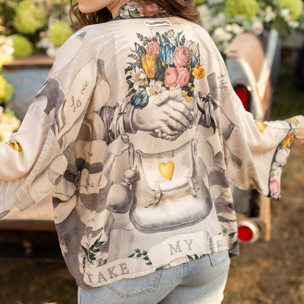 
                  
                    A joyful blend of 17th-century engravings, painted hearts, and hand-coloured florals on our cropped Take My Hand Pixie duster kimono – Market of Stars
                  
                