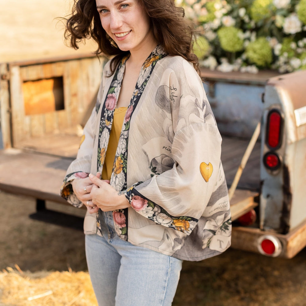 
                  
                    A joyful blend of 17th-century engravings, painted hearts, and hand-coloured florals on our cropped Take My Hand Pixie duster kimono – Market of Stars
                  
                