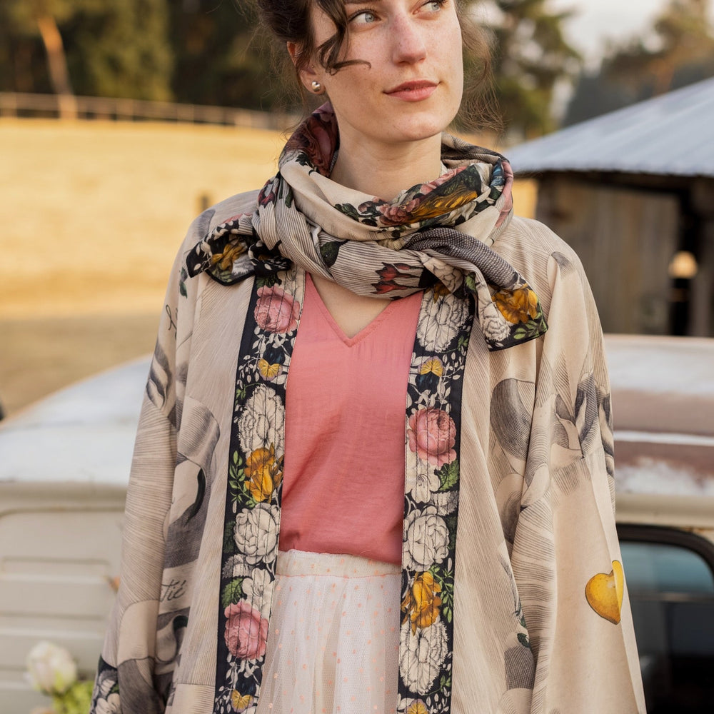 
                  
                    Model wearing Take My Hand scarf with 1600s hand engraving of clasped hands, a painted heart, florals and sun rays – Market of Stars
                  
                