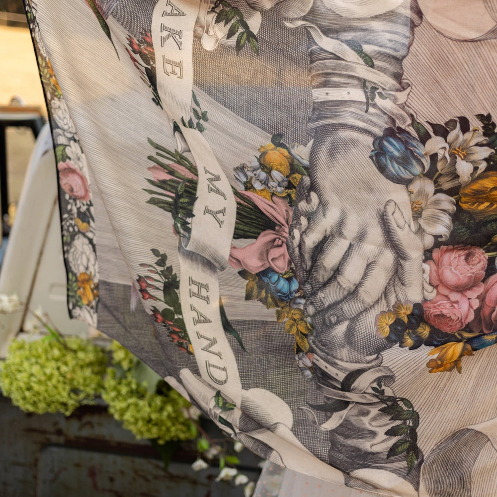 
                  
                    Model wearing Take My Hand scarf with 1600s hand engraving of clasped hands, a painted heart, florals and sun rays – Market of Stars
                  
                