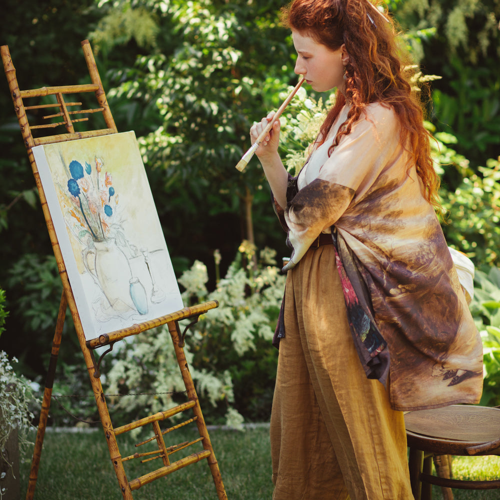
                  
                    Model wearing The Artist kimono-style duster featuring antique paintings, botanical floral trim, and a radiant golden sun – Market of Stars
                  
                