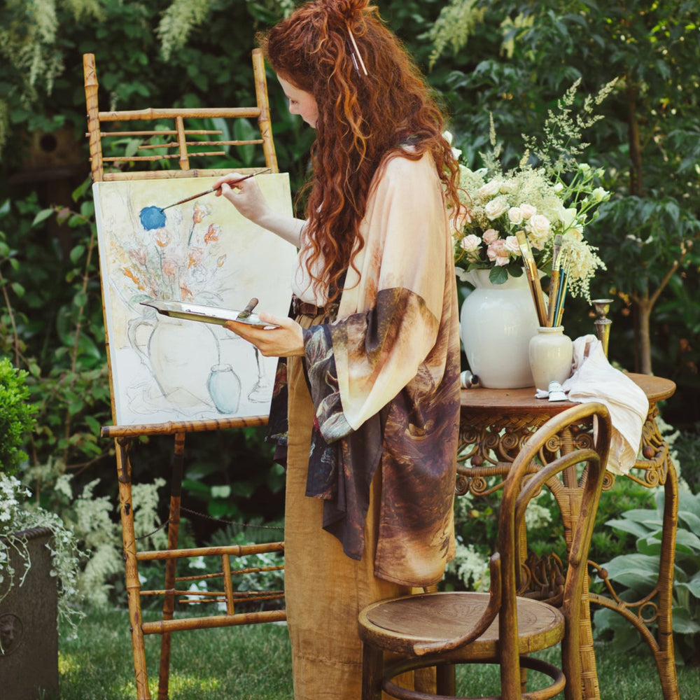 
                  
                    Model wearing The Artist kimono-style duster featuring antique paintings, botanical floral trim, and a radiant golden sun – Market of Stars
                  
                