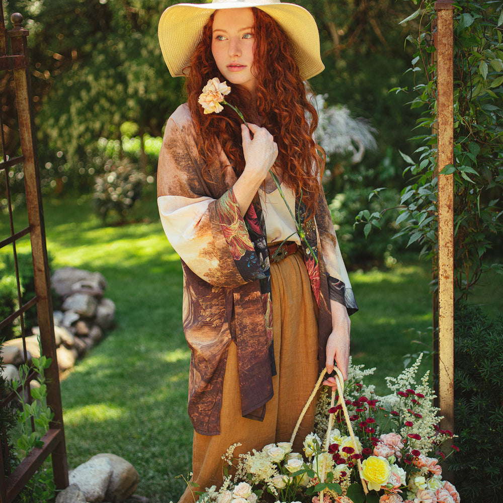 
                  
                    Model wearing The Artist kimono-style duster featuring antique paintings, botanical floral trim, and a radiant golden sun – Market of Stars
                  
                