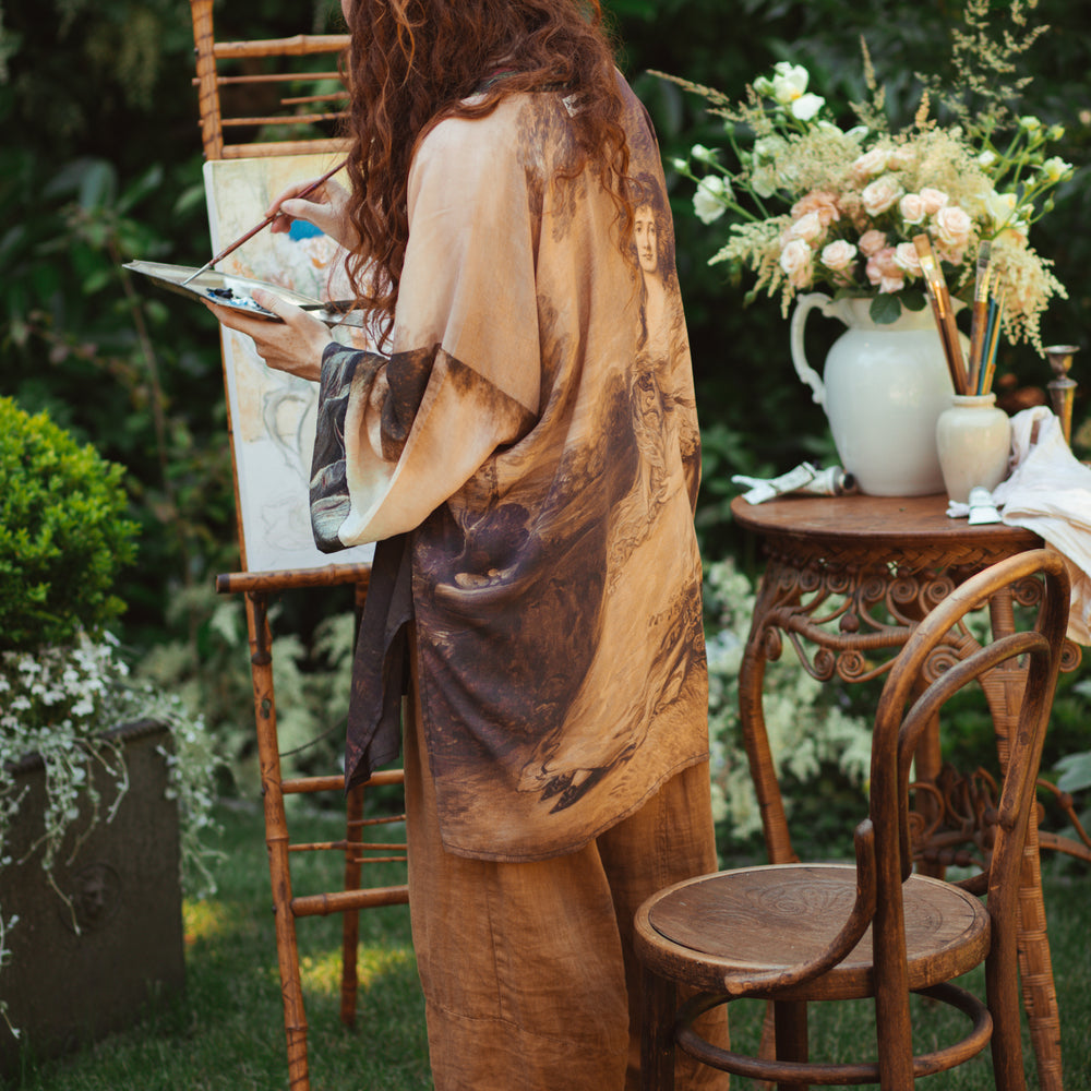 
                  
                    Model wearing The Artist kimono-style duster featuring antique paintings, botanical floral trim, and a radiant golden sun – Market of Stars
                  
                