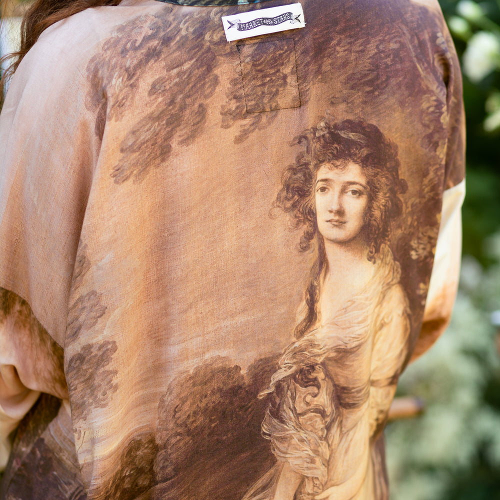 
                  
                    Model wearing The Artist kimono-style duster featuring antique paintings, botanical floral trim, and a radiant golden sun – Market of Stars
                  
                
