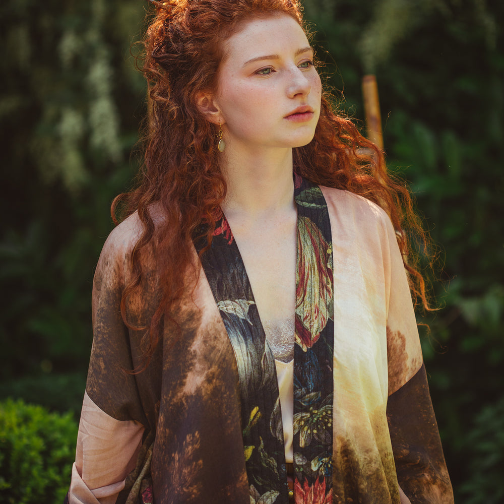 
                  
                    Model wearing The Artist kimono-style duster featuring antique paintings, botanical floral trim, and a radiant golden sun – Market of Stars
                  
                
