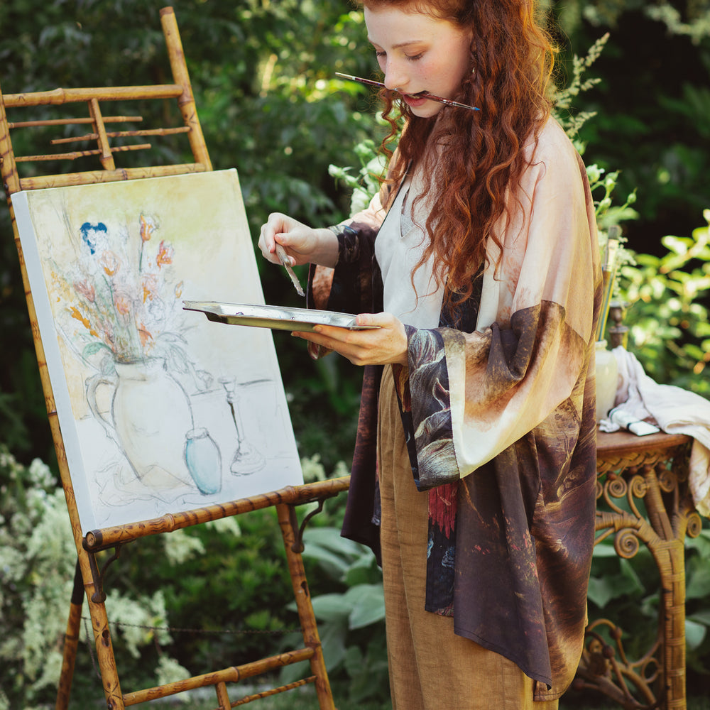 
                  
                    Model wearing The Artist kimono-style duster featuring antique paintings, botanical floral trim, and a radiant golden sun – Market of Stars
                  
                
