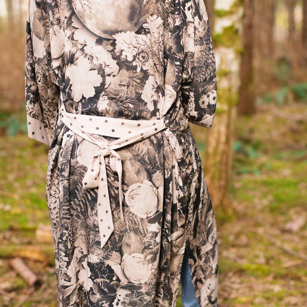
                  
                    Model wearing Looking Glass Opera Robe featuring grown-up Alice Liddell, Victorian botanicals, and celestial star and moon accents inspired by Wonderland – Market of Stars.
                  
                