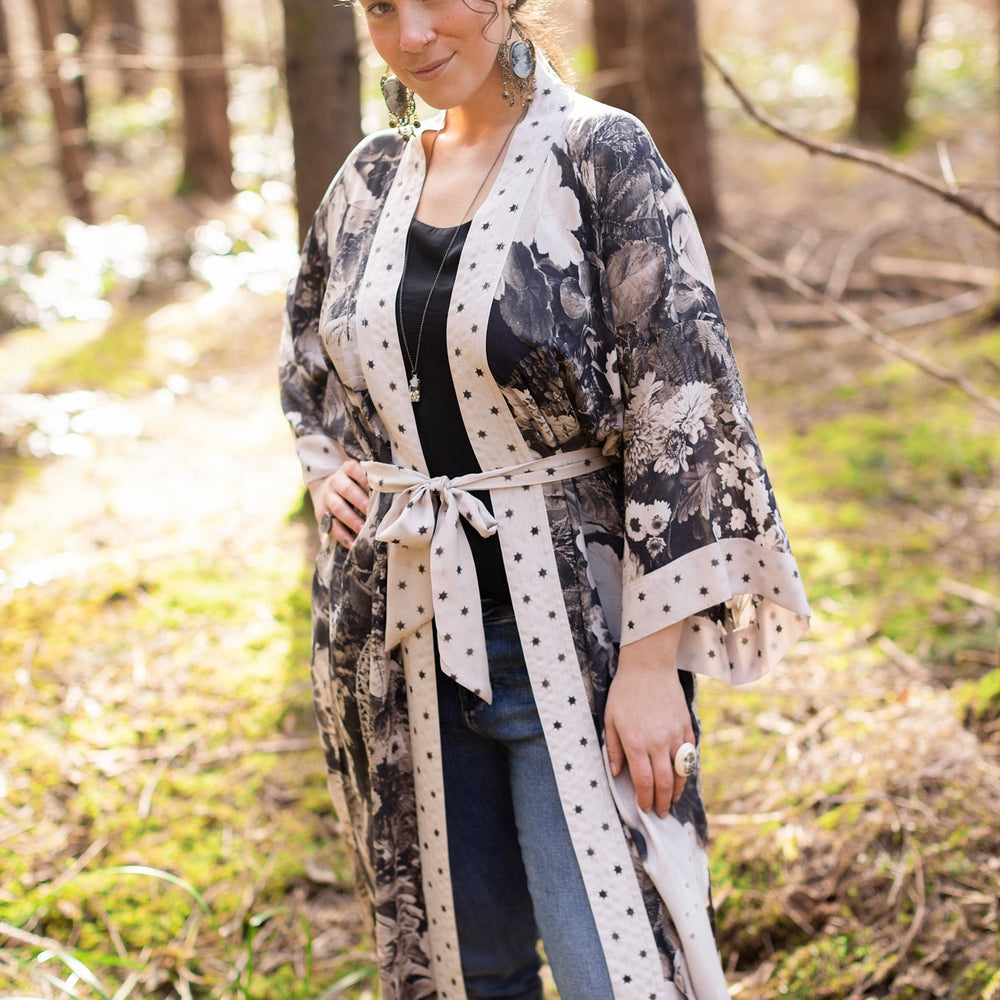 
                  
                    Model wearing Looking Glass Opera Robe featuring grown-up Alice Liddell, Victorian botanicals, and celestial star and moon accents inspired by Wonderland – Market of Stars.
                  
                