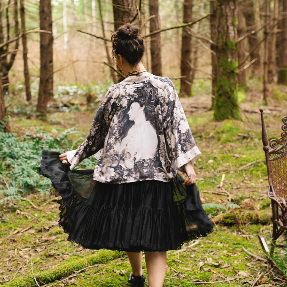 
                  
                    Model wearing Looking Glass Cropped Kimono featuring grown-up Alice Liddell, rare Victorian botanicals, and celestial star and moon accents inspired by Wonderland – Market of Stars.
                  
                