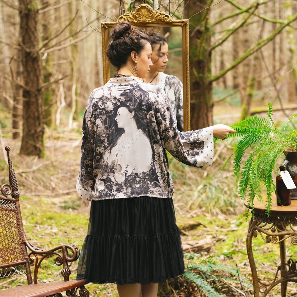 
                  
                    Model wearing Looking Glass Cropped Kimono featuring grown-up Alice Liddell, rare Victorian botanicals, and celestial star and moon accents inspired by Wonderland – Market of Stars.
                  
                
