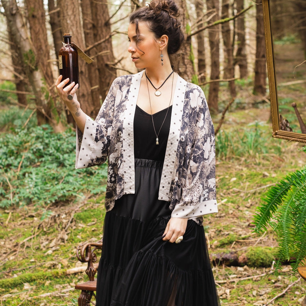 
                  
                    Model wearing Looking Glass Cropped Kimono featuring grown-up Alice Liddell, rare Victorian botanicals, and celestial star and moon accents inspired by Wonderland – Market of Stars.
                  
                