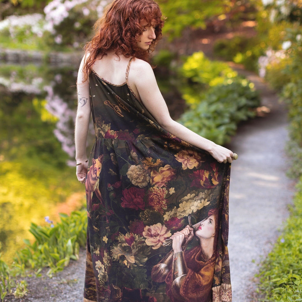 
                  
                    Model wearing a maxi-length bamboo-viscose slip dress featuring florals from centuries-old paintings and Rosetti’s iconic portrait of Joan of Arc - Market of Stars
                  
                