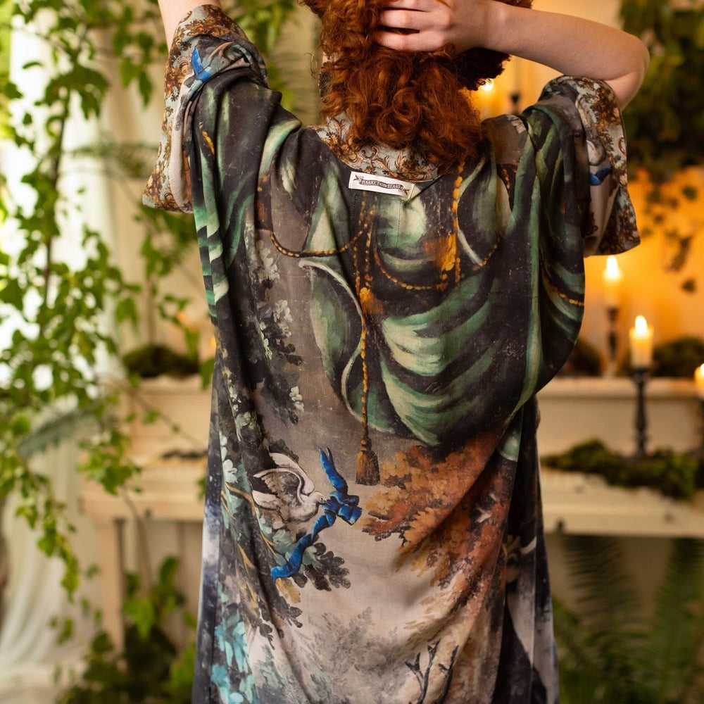 
                  
                    Model wearing the Theatre of Dreams Opera Duster featuring whimsical birds, love letters, and richly painted curtains by artist Jennifer Lanne – Market of Stars
                  
                