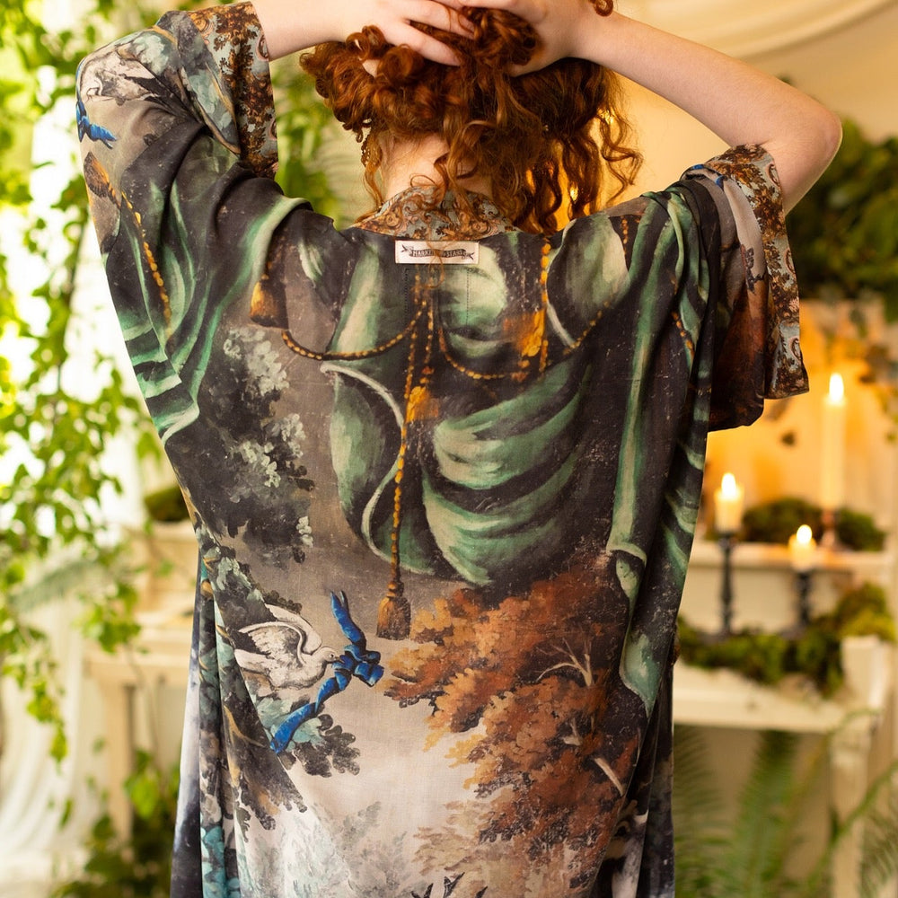 
                  
                    Model wearing the Theatre of Dreams Opera Duster featuring whimsical birds, love letters, and richly painted curtains by artist Jennifer Lanne – Market of Stars
                  
                