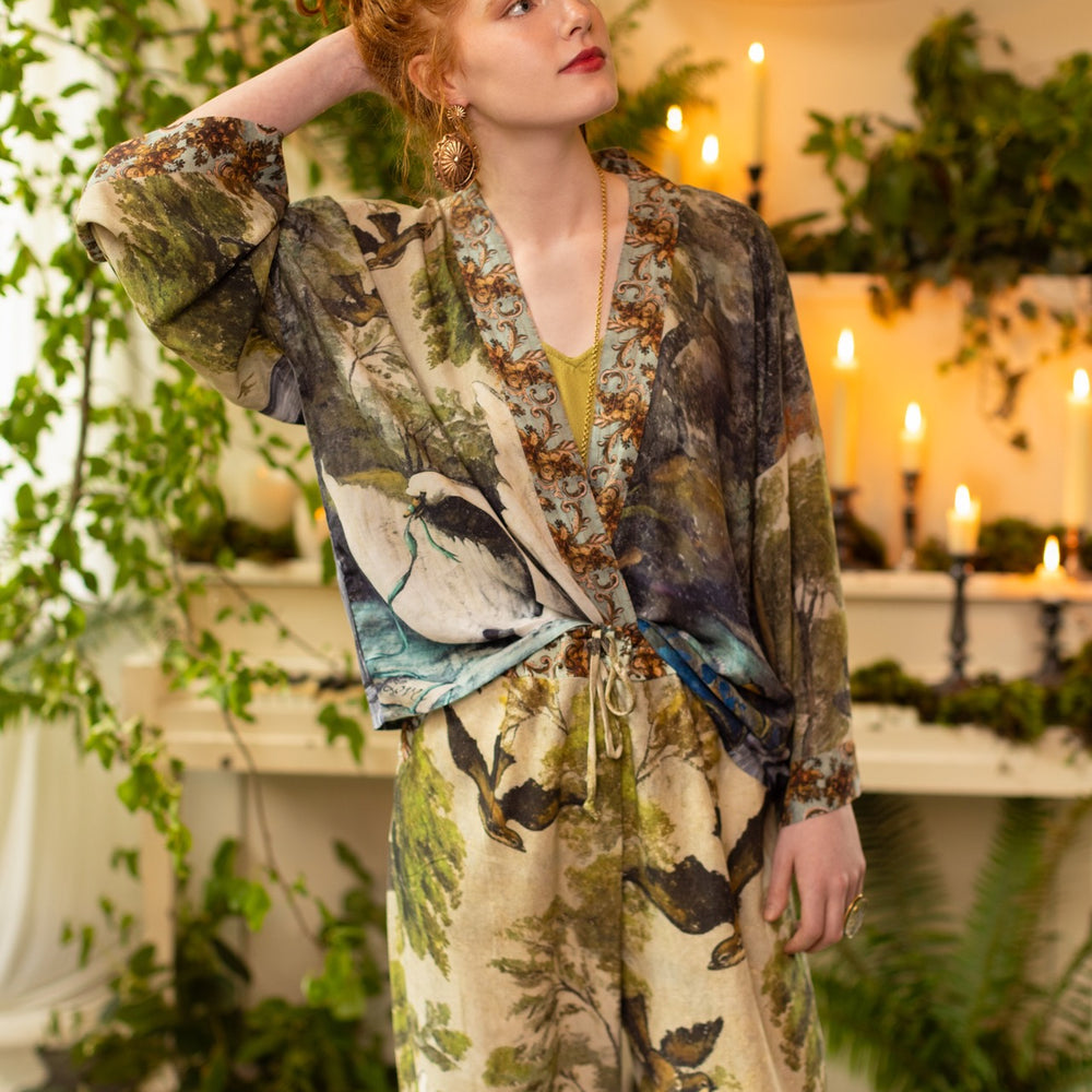 
                  
                    Model wearing the cropped Theatre of Dreams kimono featuring painted swan, antique script, and whimsical theatre imagery from artist Jennifer Lanne
                  
                