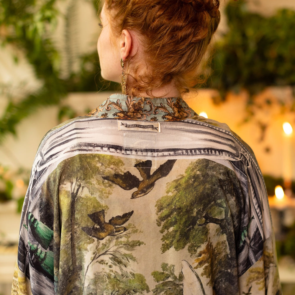 
                  
                    Model wearing the cropped Theatre of Dreams kimono featuring painted swan, antique script, and whimsical theatre imagery from artist Jennifer Lanne
                  
                