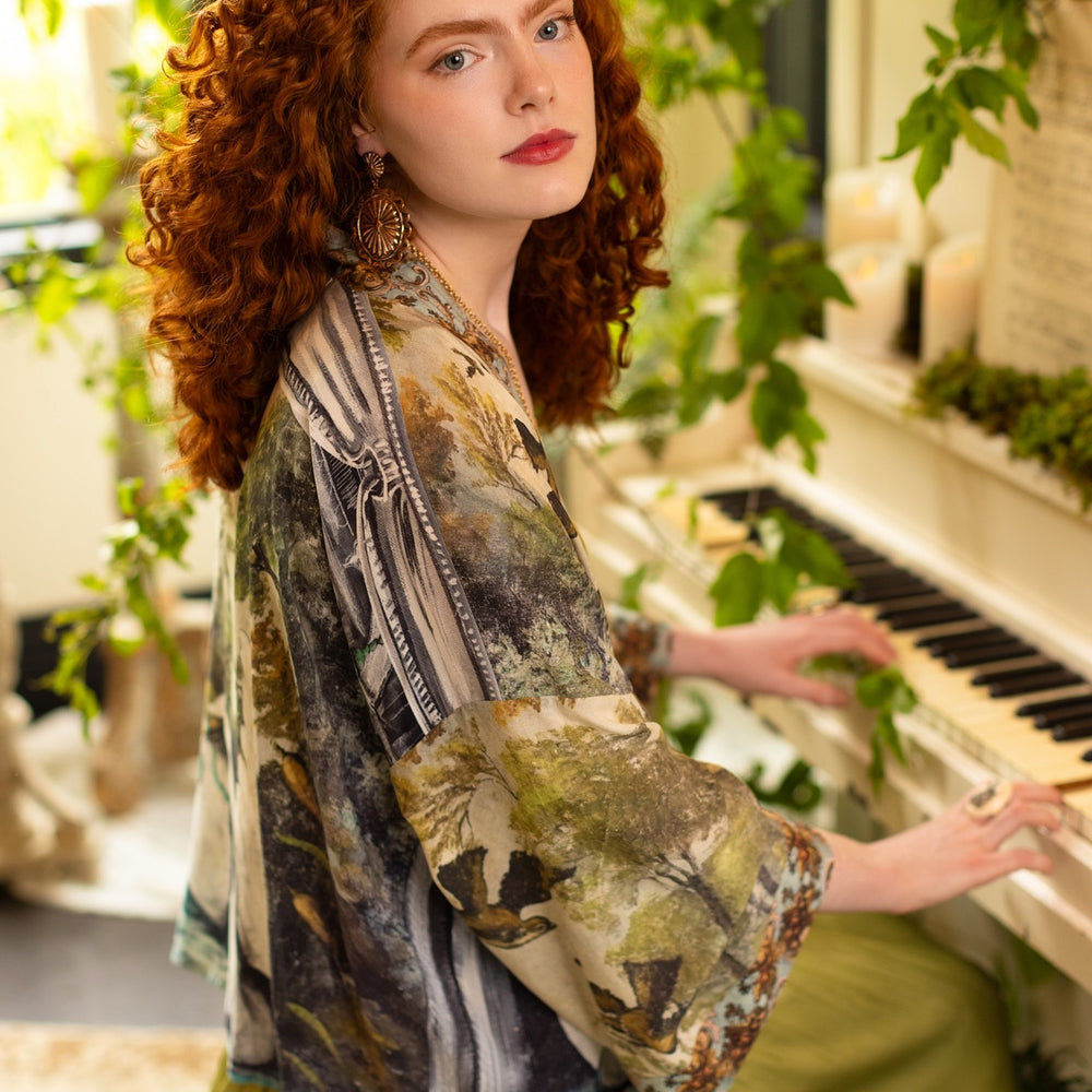 
                  
                    Model wearing the cropped Theatre of Dreams kimono featuring painted swan, antique script, and whimsical theatre imagery from artist Jennifer Lanne
                  
                