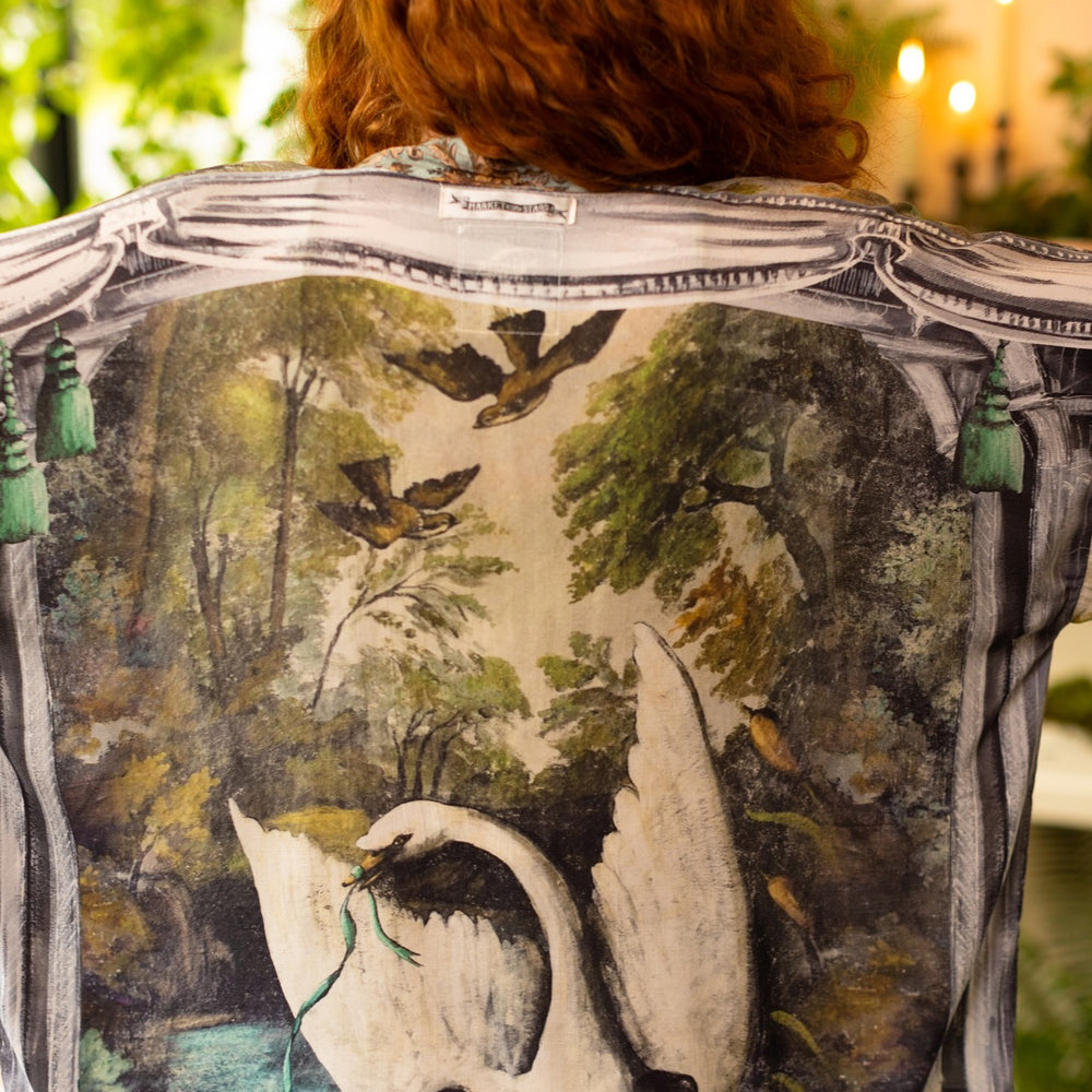
                  
                    Model wearing the cropped Theatre of Dreams kimono featuring painted swan, antique script, and whimsical theatre imagery from artist Jennifer Lanne
                  
                