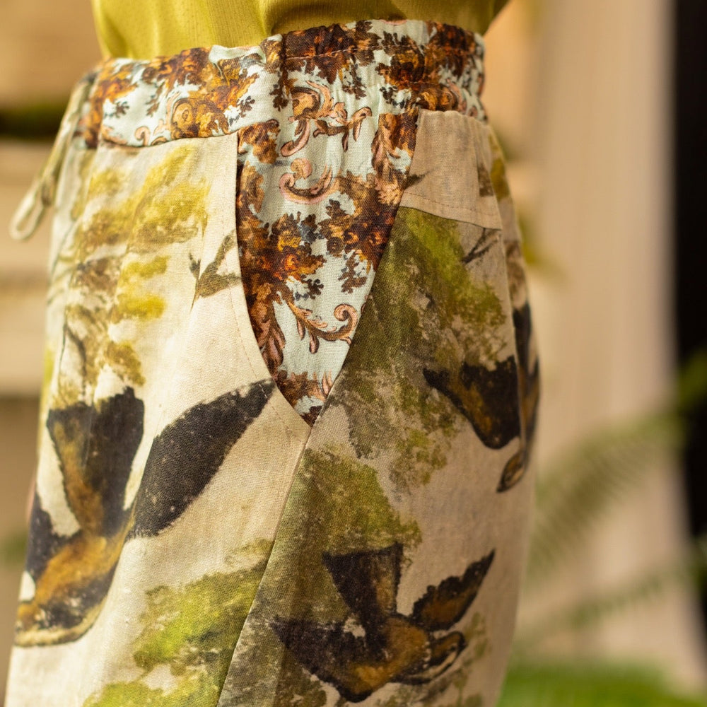 
                  
                    Model wearing Theatre of Dreams Artist Pants with lantern-hem silhouette featuring antique landscape, swan, and painted birds by artist Jennifer Lanne
                  
                