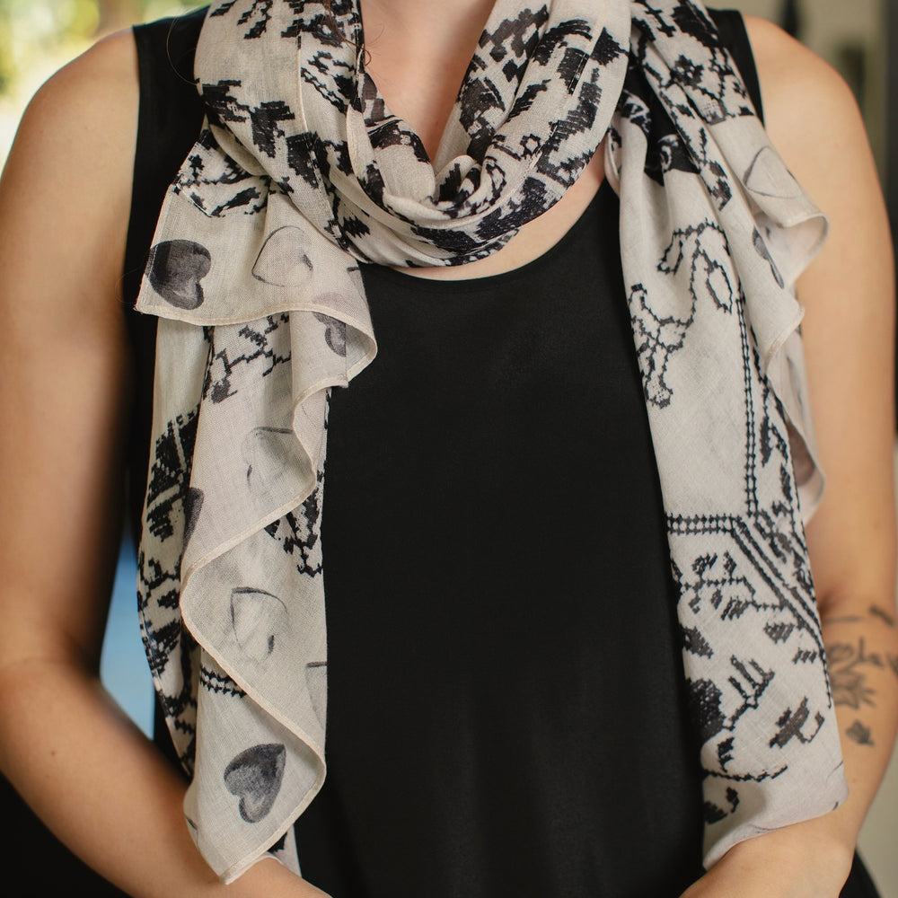
                  
                    Model wearing the Token of Love scarf featuring black and ivory printed antique cross-stitch – Market of Stars
                  
                