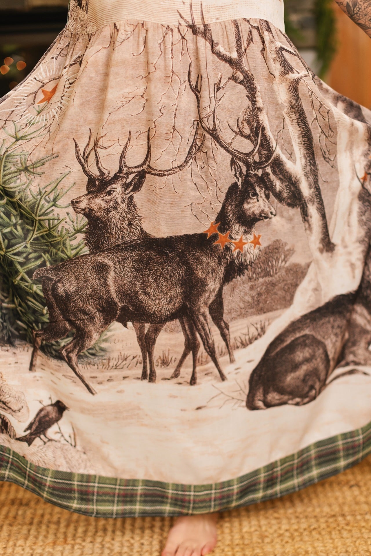 Model wearing a bamboo viscose maxi slip dress with Victorian-era images from holiday greeting cards — including reindeer in the snow, a little fir tree, golden stars, and traditional plaid trim - Market of Stars
