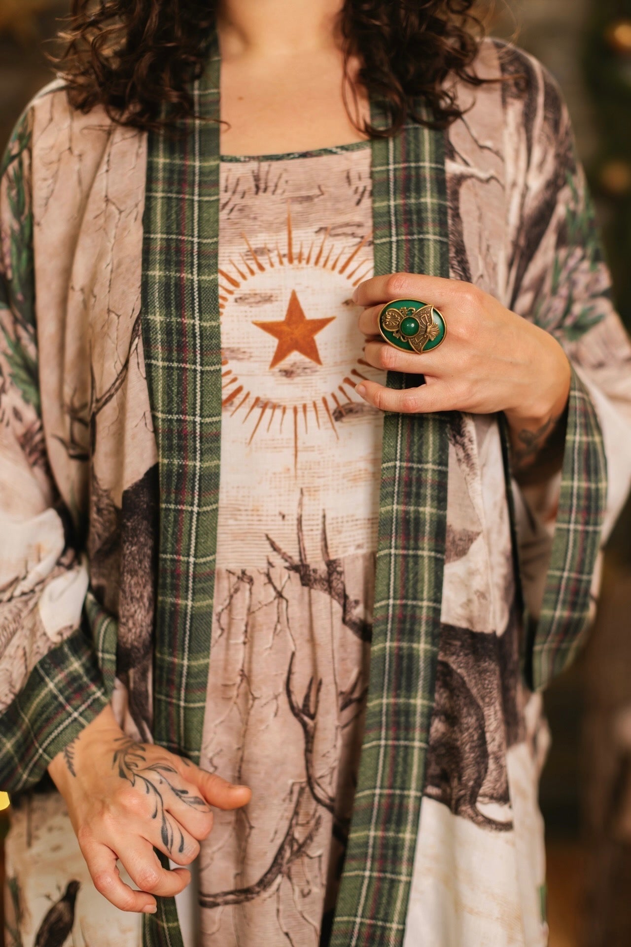 Model wearing a bamboo viscose mid-length duster with Victorian-era images from holiday greeting cards — including reindeer in the snow, a little fir tree, golden stars, and traditional plaid trim - Market of Stars