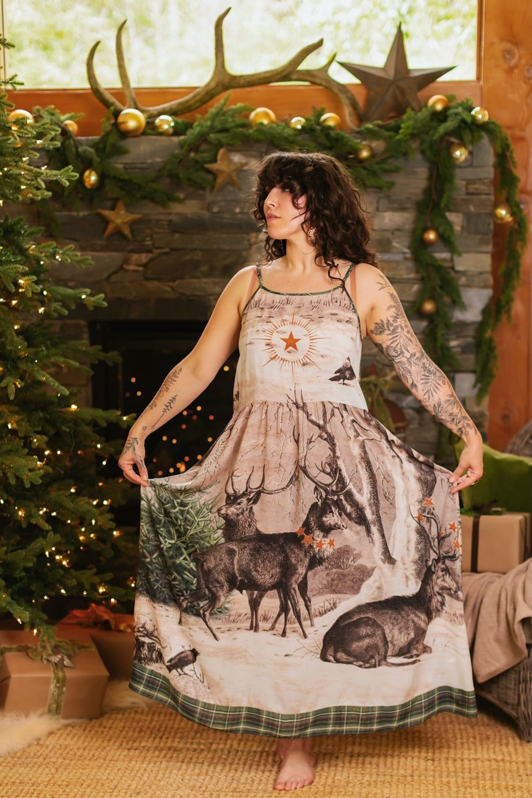 Model wearing a bamboo viscose maxi slip dress with Victorian-era images from holiday greeting cards — including reindeer in the snow, a little fir tree, golden stars, and traditional plaid trim - Market of Stars