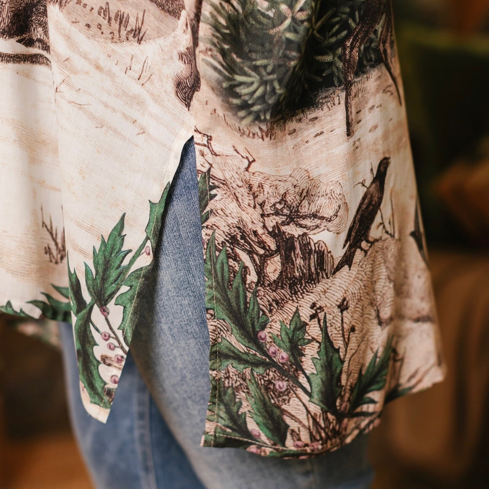
                  
                    Model wearing a bamboo viscose mid-length duster with Victorian-era images from holiday greeting cards — including reindeer in the snow, a little fir tree, golden stars, and traditional plaid trim - Market of Stars
                  
                