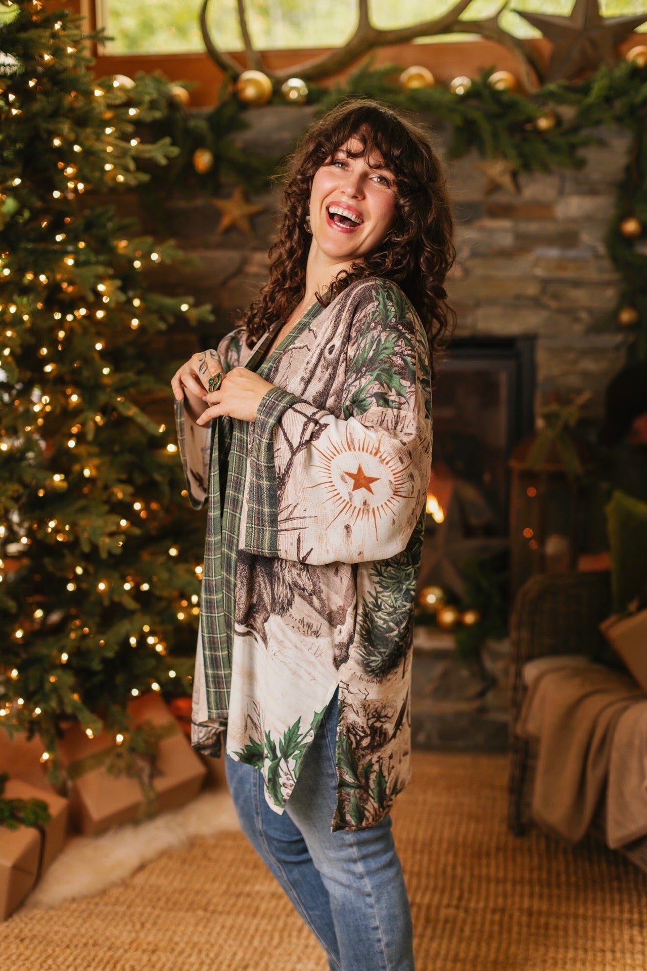 Model wearing a bamboo viscose mid-length duster with Victorian-era images from holiday greeting cards — including reindeer in the snow, a little fir tree, golden stars, and traditional plaid trim - Market of Stars