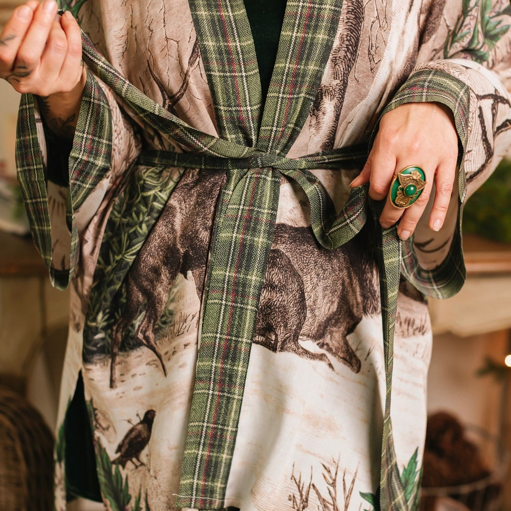 
                  
                    Model wearing a bamboo viscose mid-length duster with Victorian-era images from holiday greeting cards — including reindeer in the snow, a little fir tree, golden stars, and traditional plaid trim - Market of Stars
                  
                