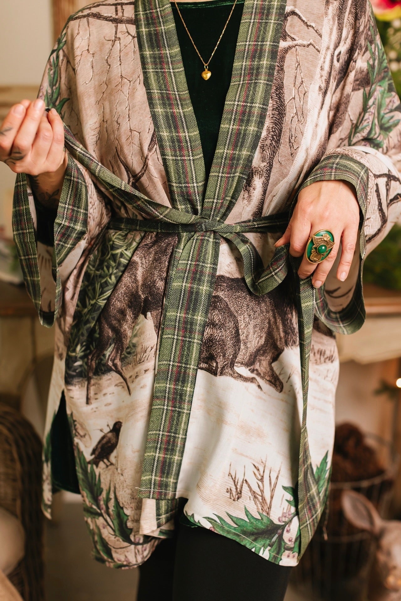 Model wearing a bamboo viscose mid-length duster with Victorian-era images from holiday greeting cards — including reindeer in the snow, a little fir tree, golden stars, and traditional plaid trim - Market of Stars