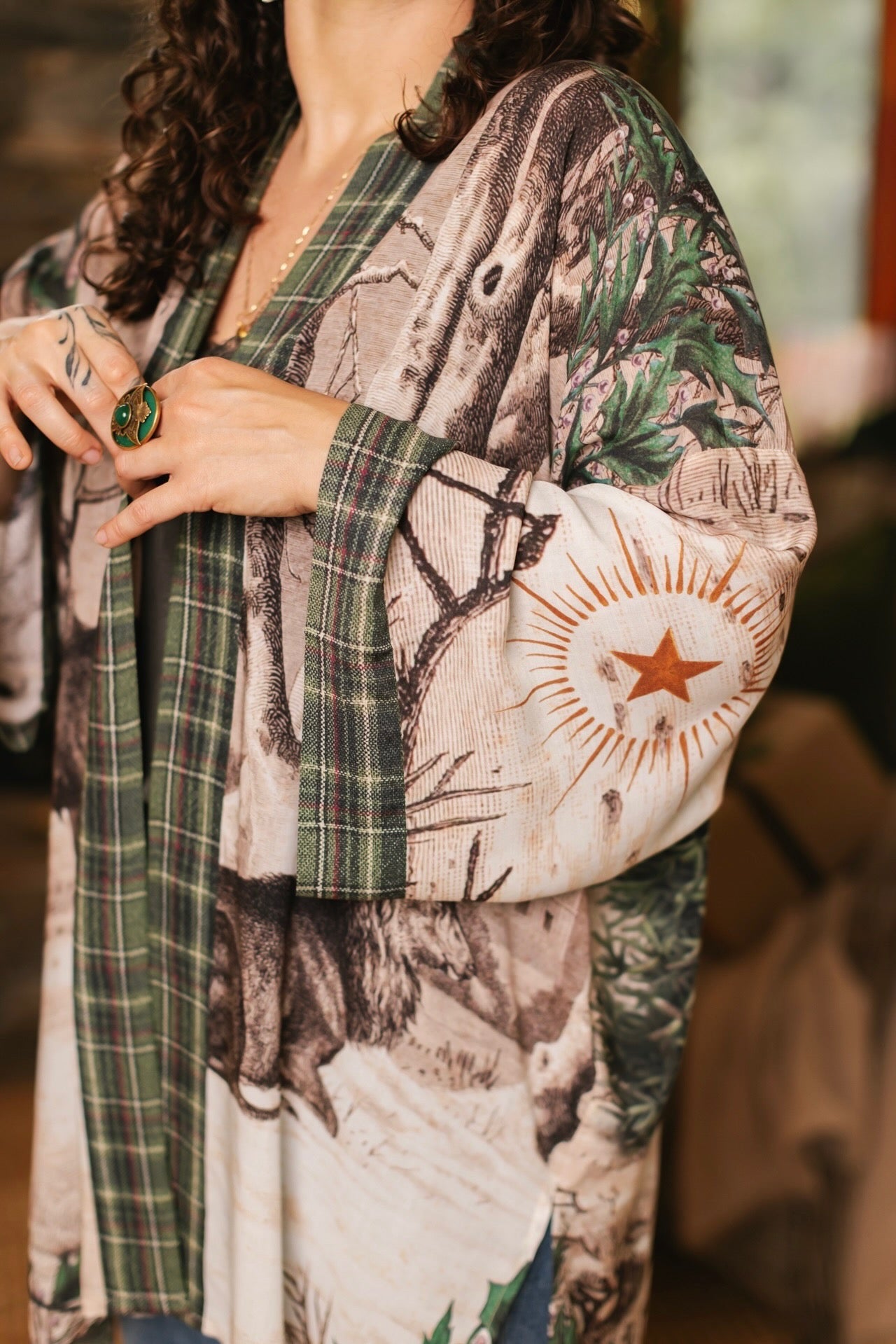 Model wearing a bamboo viscose mid-length duster with Victorian-era images from holiday greeting cards — including reindeer in the snow, a little fir tree, golden stars, and traditional plaid trim - Market of Stars