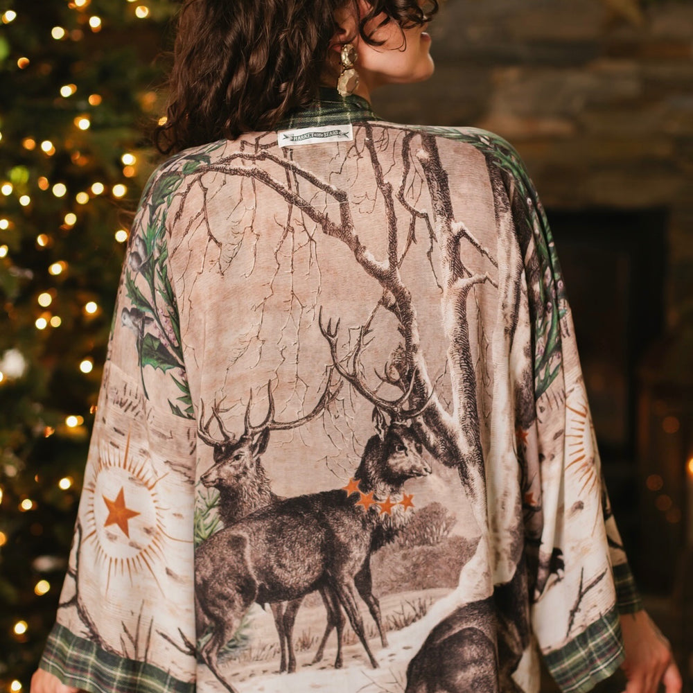 
                  
                    Model wearing a bamboo viscose mid-length duster with Victorian-era images from holiday greeting cards — including reindeer in the snow, a little fir tree, golden stars, and traditional plaid trim - Market of Stars
                  
                