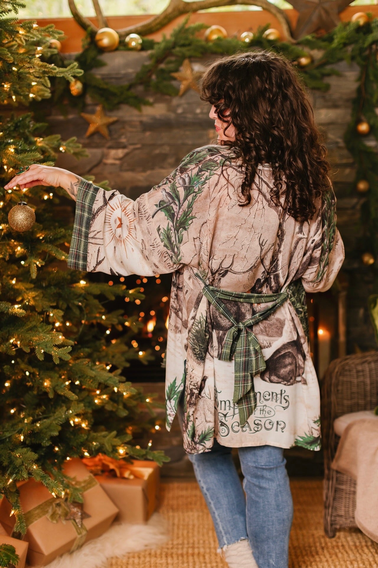 Model wearing a bamboo viscose mid-length duster with Victorian-era images from holiday greeting cards — including reindeer in the snow, a little fir tree, golden stars, and traditional plaid trim - Market of Stars